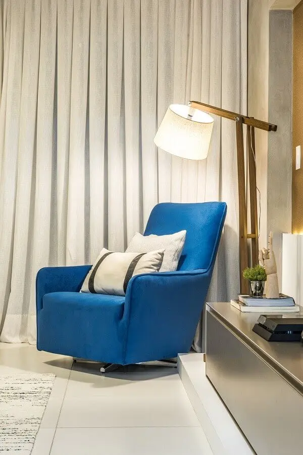 sala com poltrona azul confortável e abajur de chão Foto Daniel Dantas