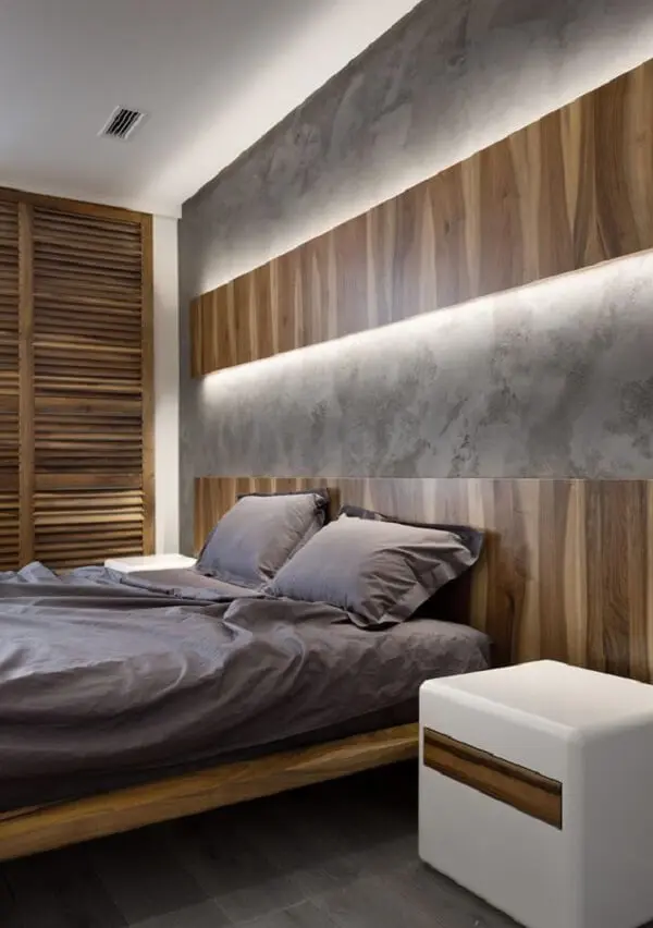 A arandela de madeira ocupa todo o espaço acima da cabeceira da cama