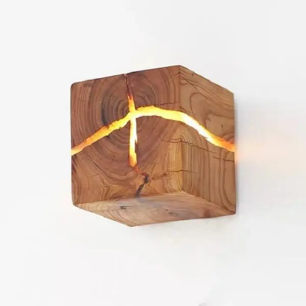 Arandela de madeira rústica com ranhuras que permitem a passagem da luz