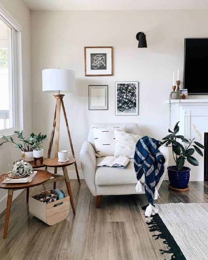 Decoração de sala branca com poltrona confortável e mesa de apoio de madeira Foto Hofdeco