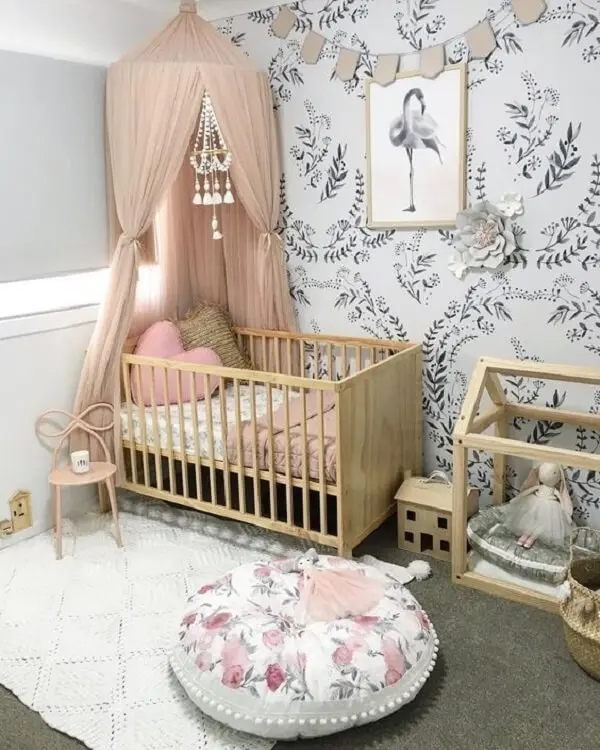 Modelo de berço cor de madeira crua e puff redondo estampado decoram o quarto de bebê