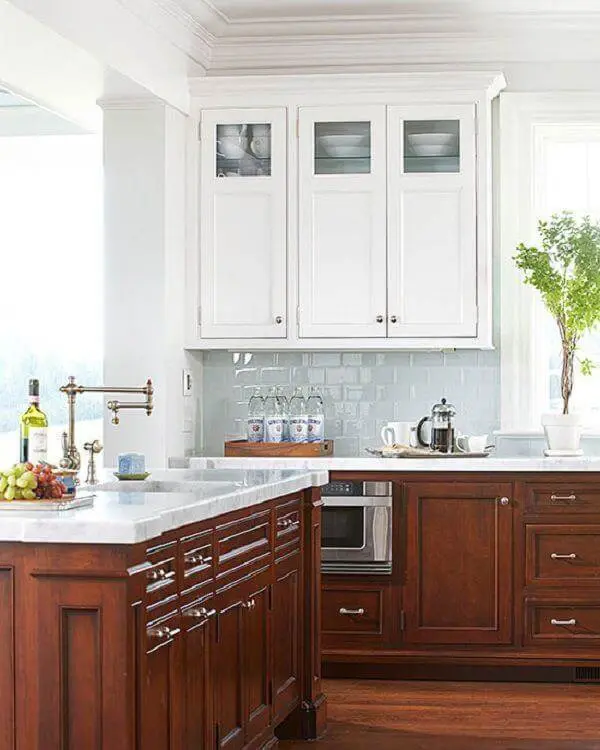 O armário de cozinha cor de madeira escura com tampo de granito branco encantam a decoração