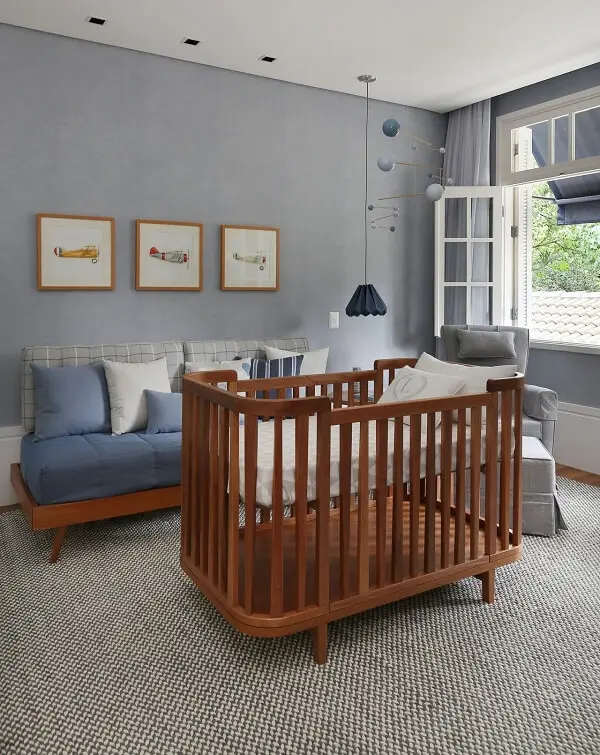 O berço cor de madeira quebra a frieza do tom cinza do quarto de bebê