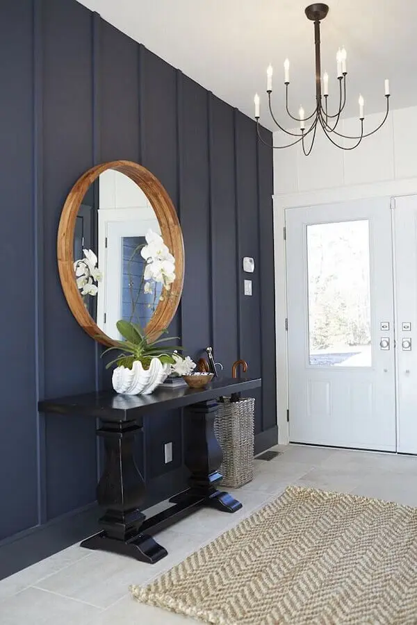 aparador para hall de entrada clássico decorado com parede azul marinho e espelho redondo de madeira Foto Jeito de Casa