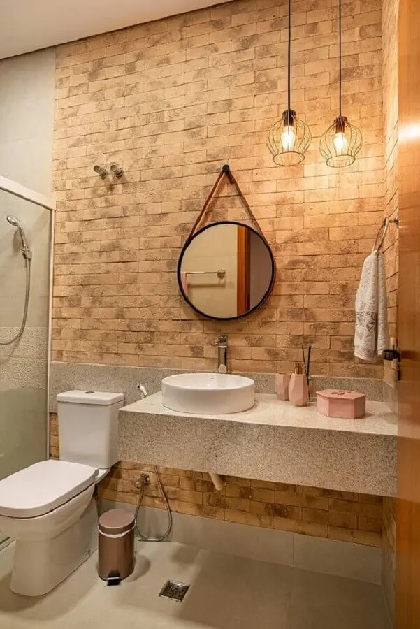 banheiro decorado com parede de tijolo e espelho redondo com moldura e alça Foto Casa de Valentina