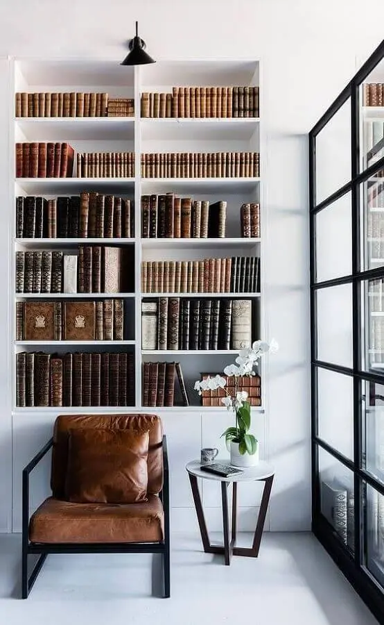 decoração minimalista com estante branca planejada e poltrona de couro para leitura Foto Futurist Architecture