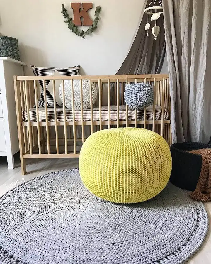 puff colorido para quarto de bebê decorado com tapete cinza e berço de madeira Foto Krona Store