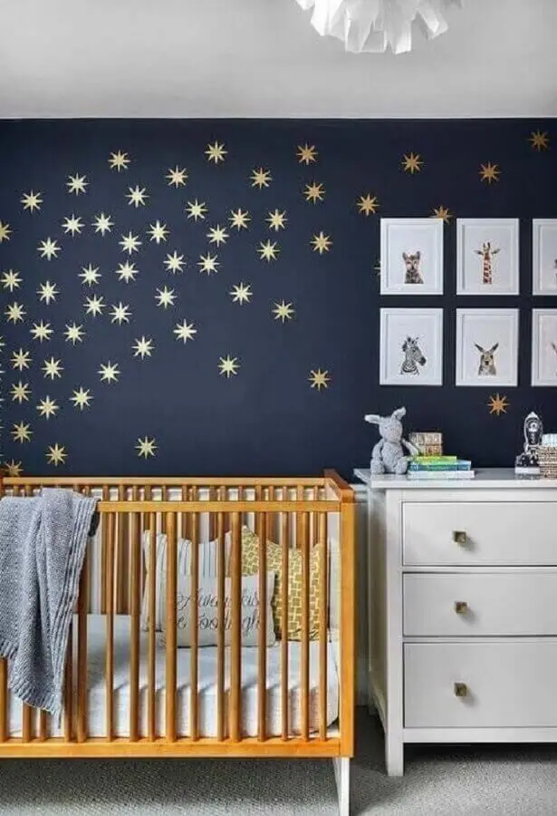 quarto de bebê azul marinho decorado com estrelinhas douradas na parede e berço de madeira Foto Pinterest