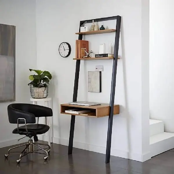 A cadeira preta giratória serve de acesso para a escrivaninha de ferro e madeira