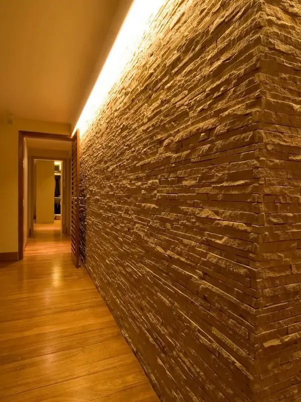 A luminária para corredor pequeno ilumina a área de passagem e realça a parede revestida com pedra canjiquinha