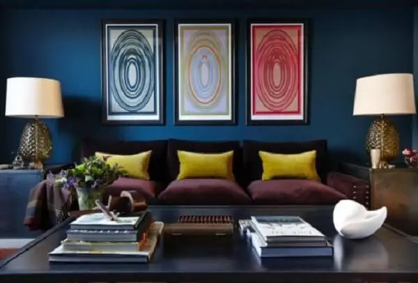As almofadas amarelas sobra o sofá roxo trazem luz para a decoração