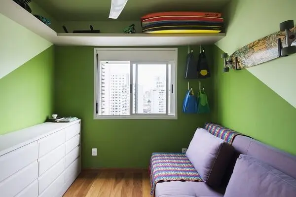 Dormitório criativo com paredes em tom verde e sofá cama roxo
