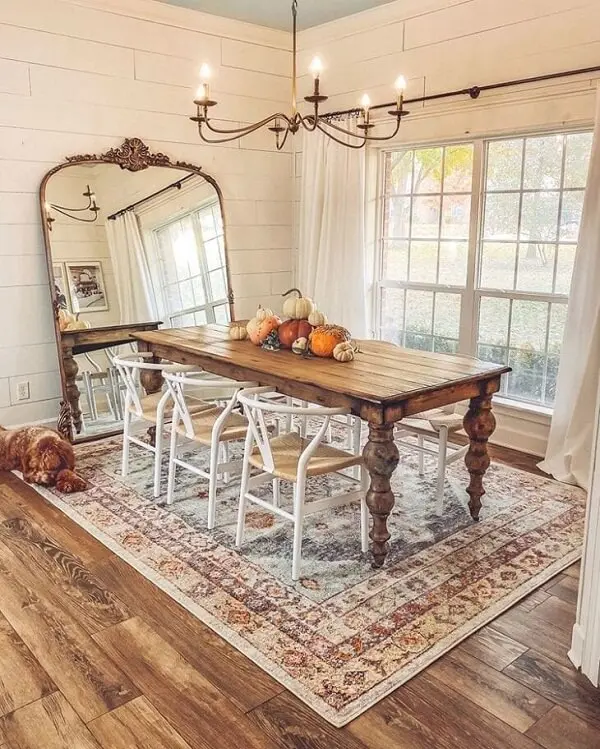 Espelho vintage de chão combinado com o acabamento do lustre realçam a beleza da sala de jantar