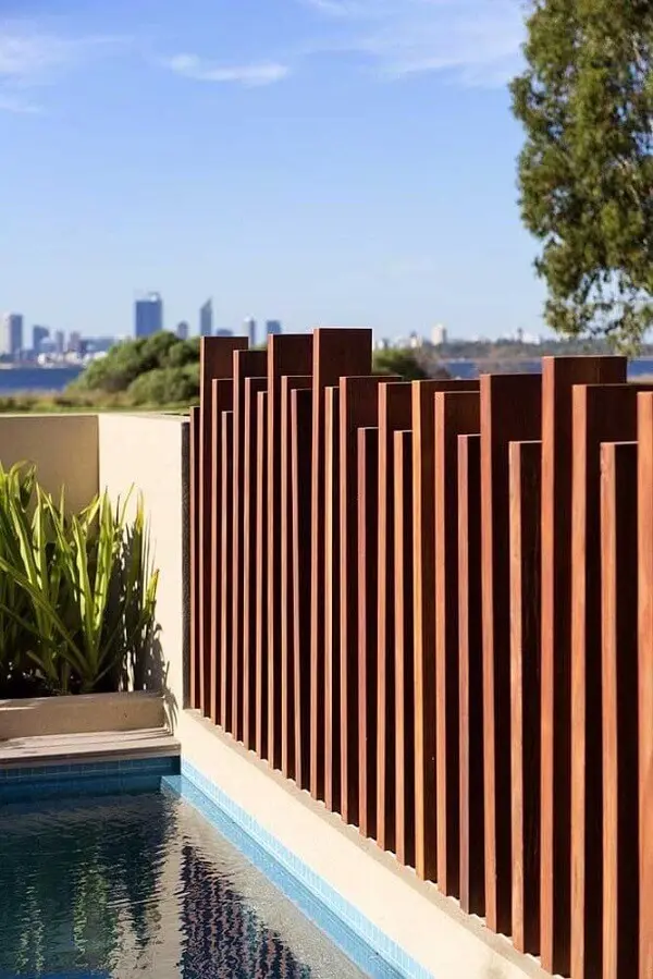 Modelo de muro moderno feito em madeira traz privacidade para a área da piscina