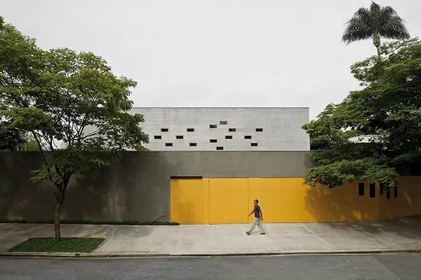 O portão amarelo se destaca nesse modelo de muro