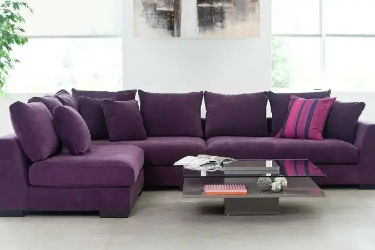 O sofá de canto roxo acomoda familiares e amigos no ambiente