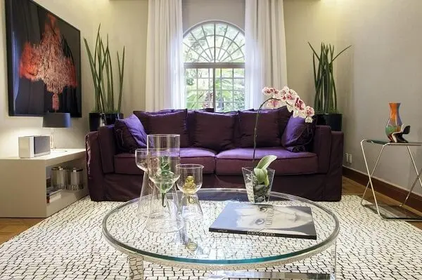 O sofá roxo contrasta com as cores claras das paredes e tapete da sala de estar