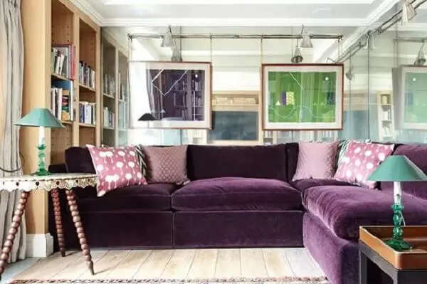 O sofá roxo de canto delimita a área da sala
