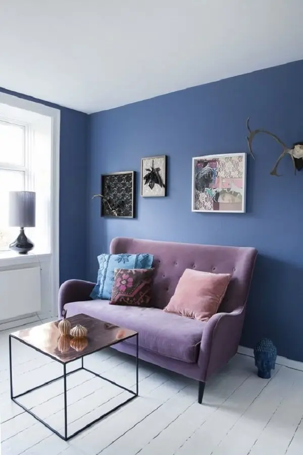 Parede azul e sofá roxo formam uma combinação ousada