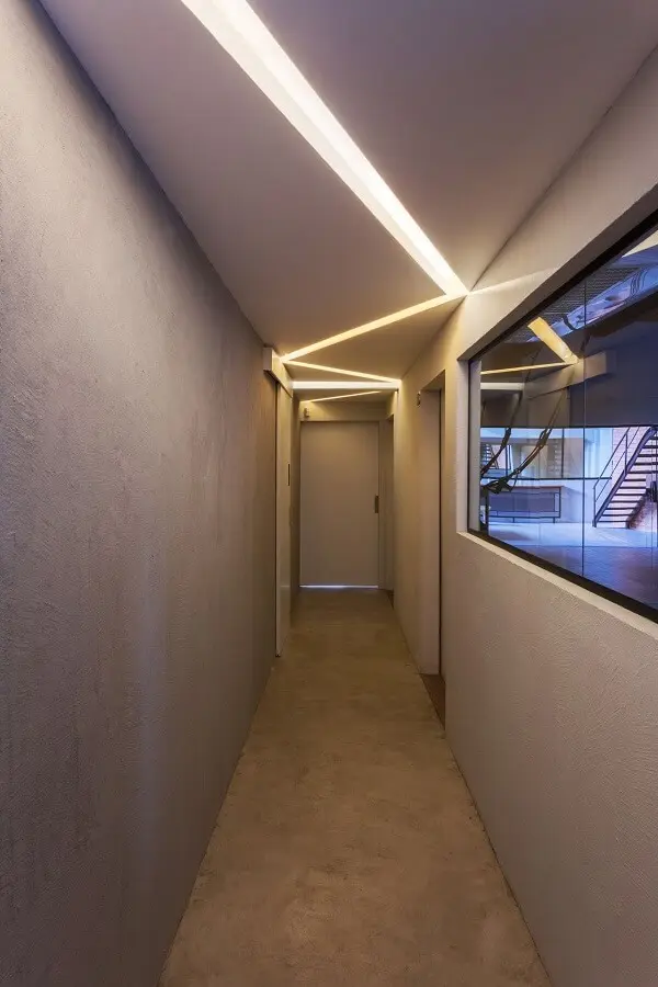 Parede com pintura cinza e luminária para corredor interno embutida forma um lindo recorte iluminado no teto