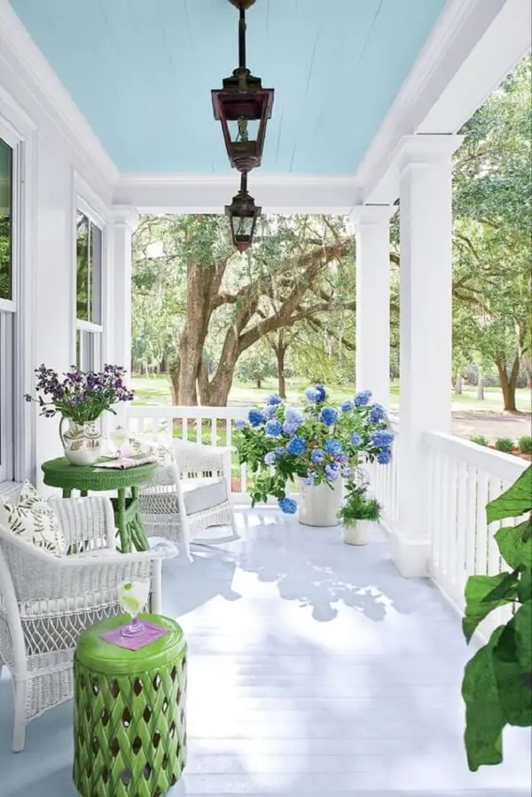 Terraço com decoração suave em tons de azul, branco e verde contam com a presença da charmosa arandela colonial
