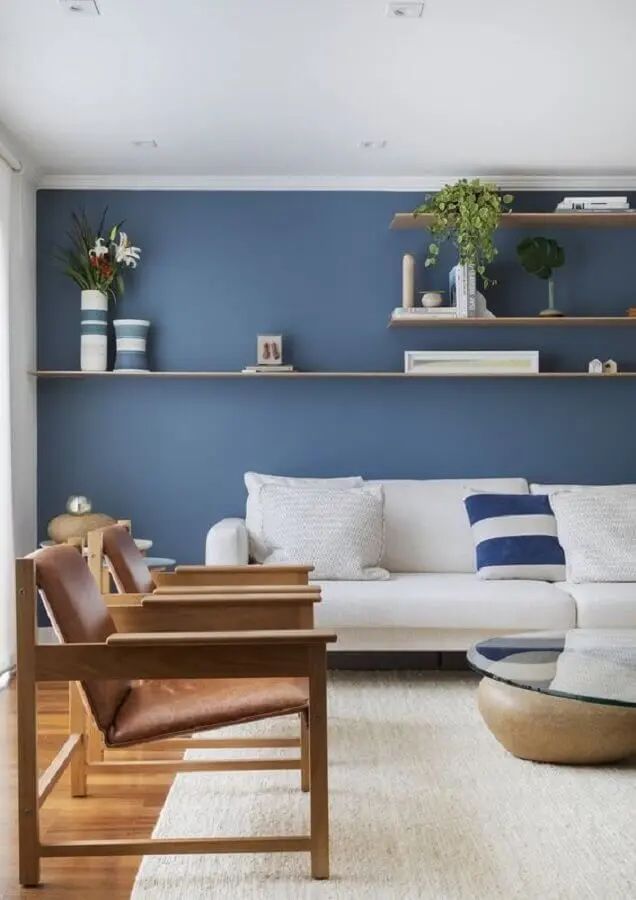 parede na cor azul para decoração de sala com sofá branco e poltronas de madeira  Foto VOA Arquitetura