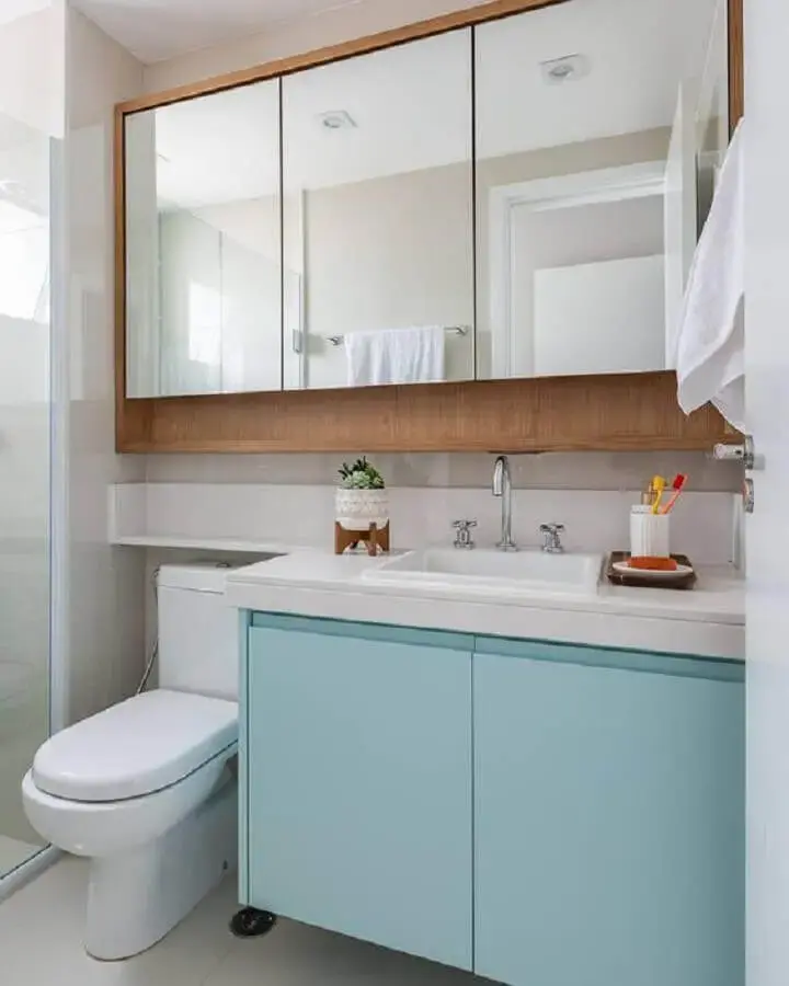 Decoração com espelheira de madeira e armario de banheiro pequeno azul claro e branco