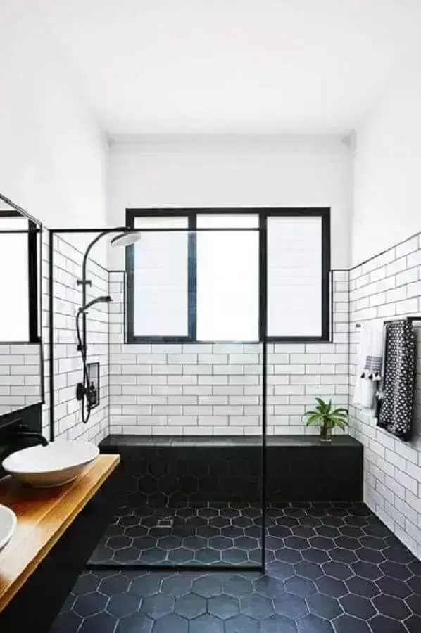 Decoração de banheiro com piso preto hexagonal e bancada de madeira