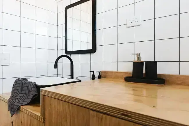 Combine móveis de madeira com tons de branco e preto e traga um toque moderno para o banheiro social