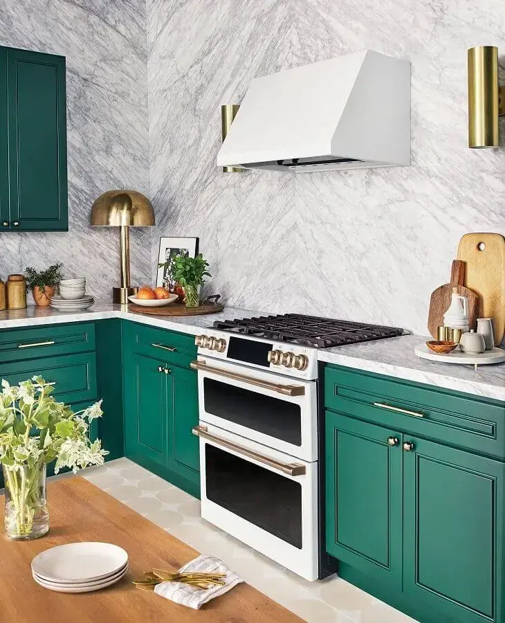 Decoração de cozinha com revestimento de mármore e armário planejado na cor verde esmeralda com puxadores dourados