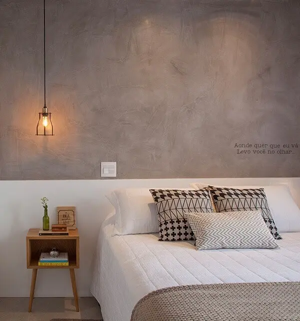 A parede de cimento queimado e a mesa de cabeceira retrô trazem personalidade para o quarto