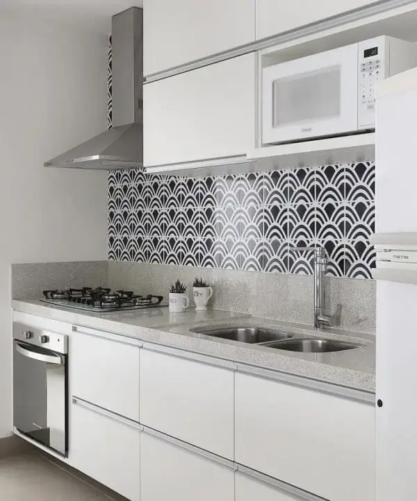 Armário basculante com acabamento branco e revestimento de parede estampado decoram a cozinha