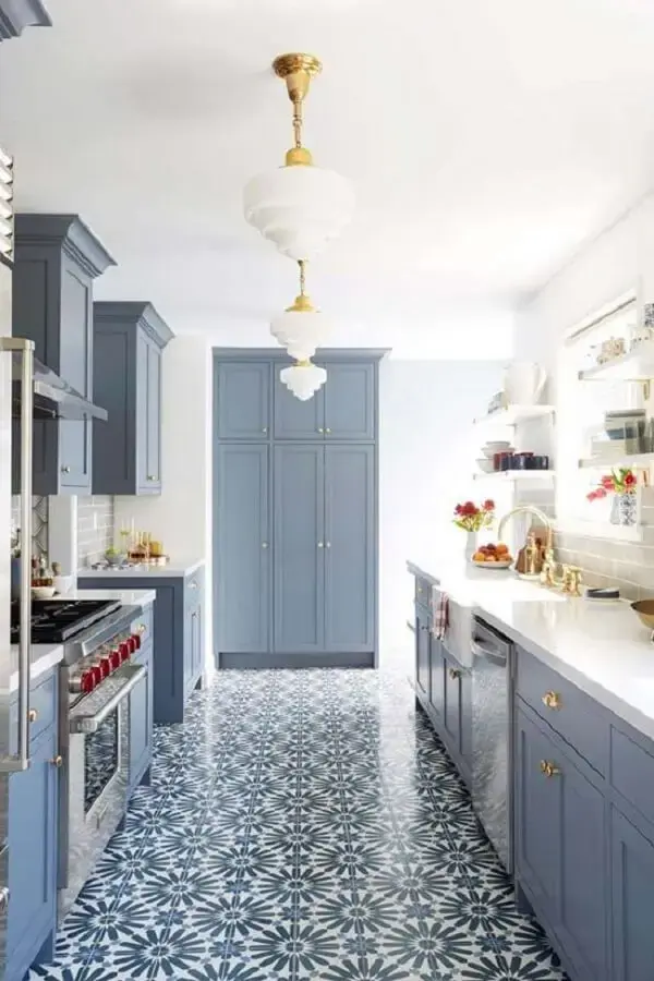 Azulejo antigo português no chão e móveis em tom azul suave decoram a cozinha