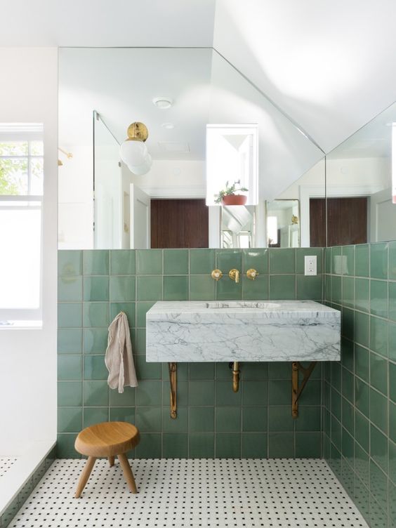 Banheiro com revestimento verde e espelho na parede
