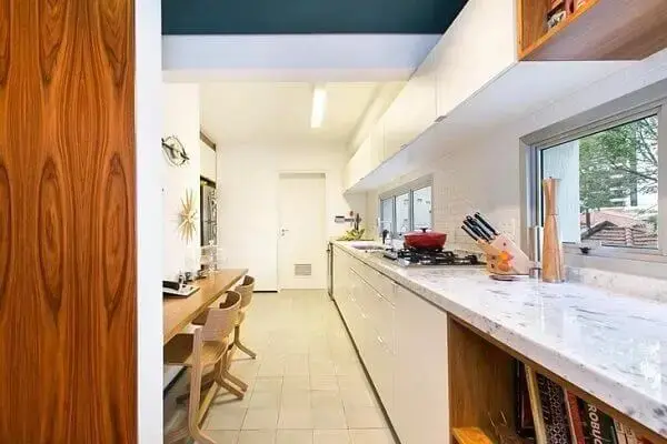 Cozinha com tampo de mármore e armário basculante que se estende por todo o ambiente