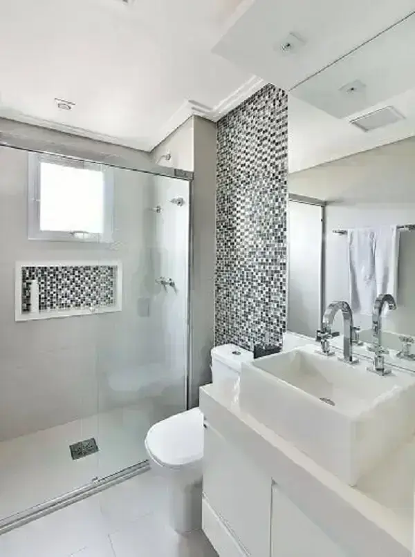 Decoração de banheiro com pastilha preta e branca, com destaque para o nicho do box e parede atrás do vaso sanitário