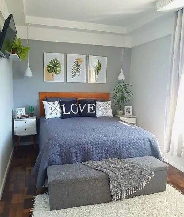 Decoração de quarto de casal com quadros de folhas e mesa cabeceira retrô branca