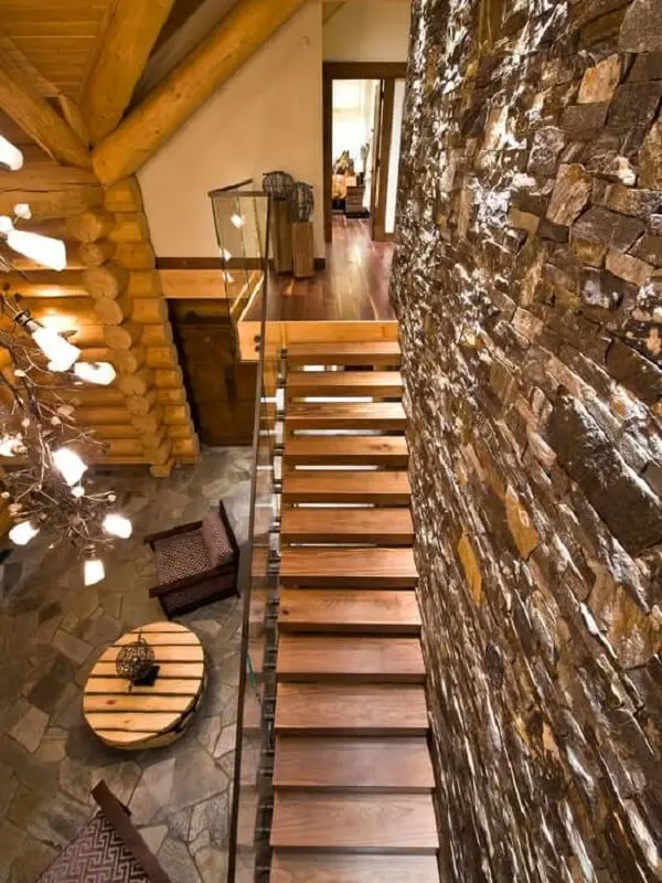Decoração rústica com parede de pedra e revestimento para escada em madeira