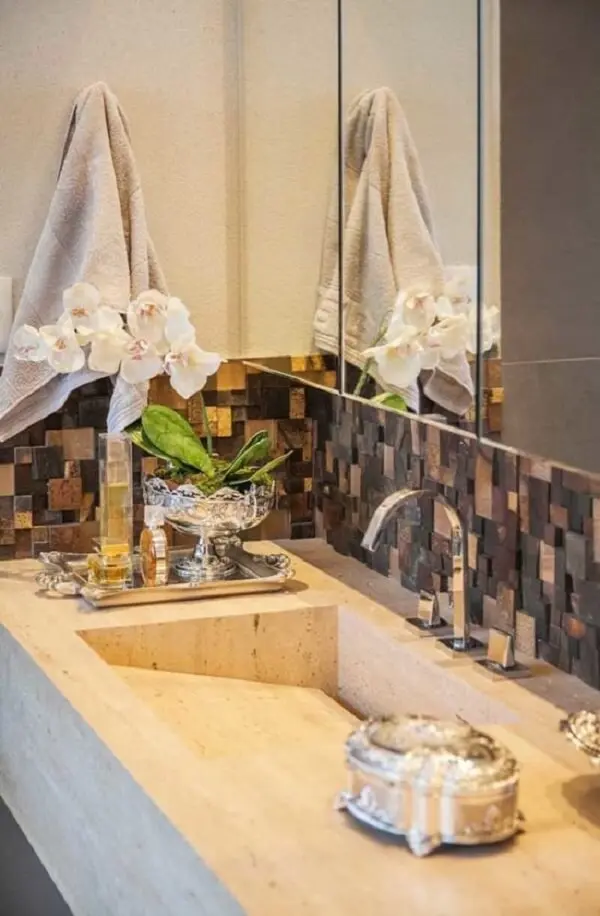 Detalhe sobre a bancada do banheiro ganha um toque sofisticado na presença do revestimento de pedra ferro