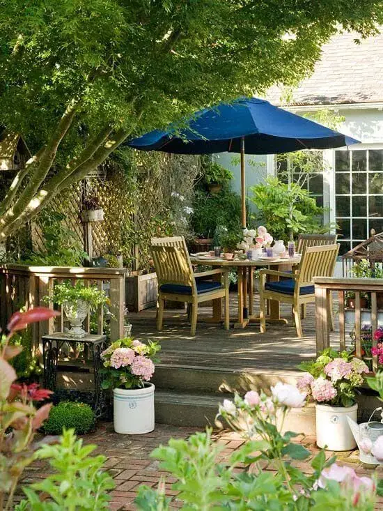 Jardim com mesa para área externa e guarda sol azul