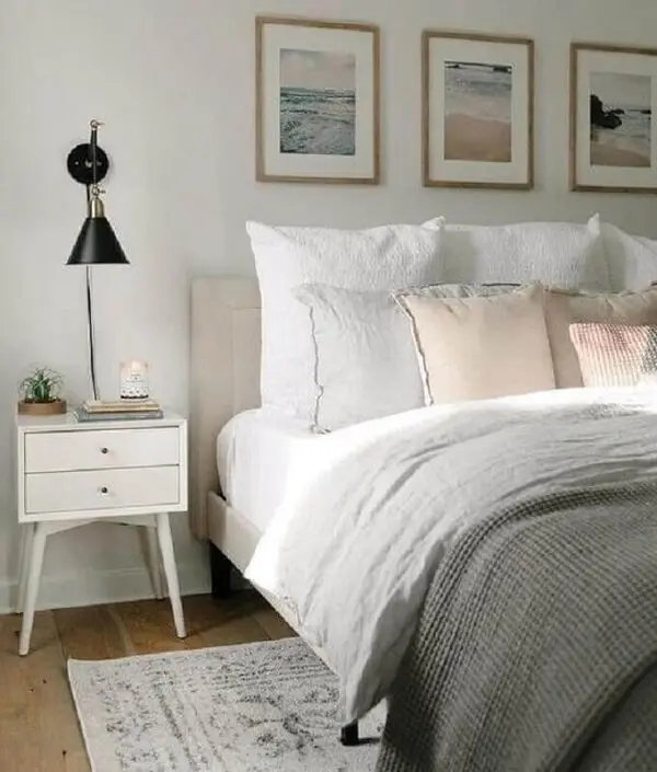 Mesa de cabeceira retrô branca decora o quarto de casal com arandela preta moderna