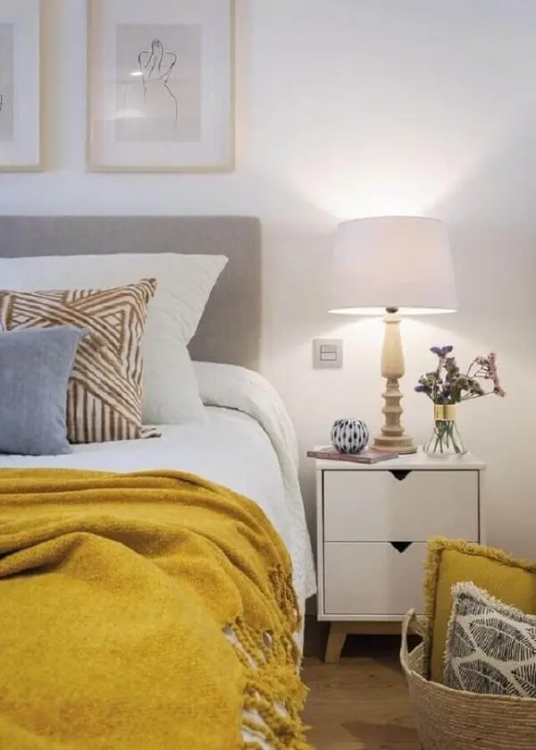 Mesa de cabeceira retrô com gavetas para decoração de quarto branco com manta amarela sobre a cama