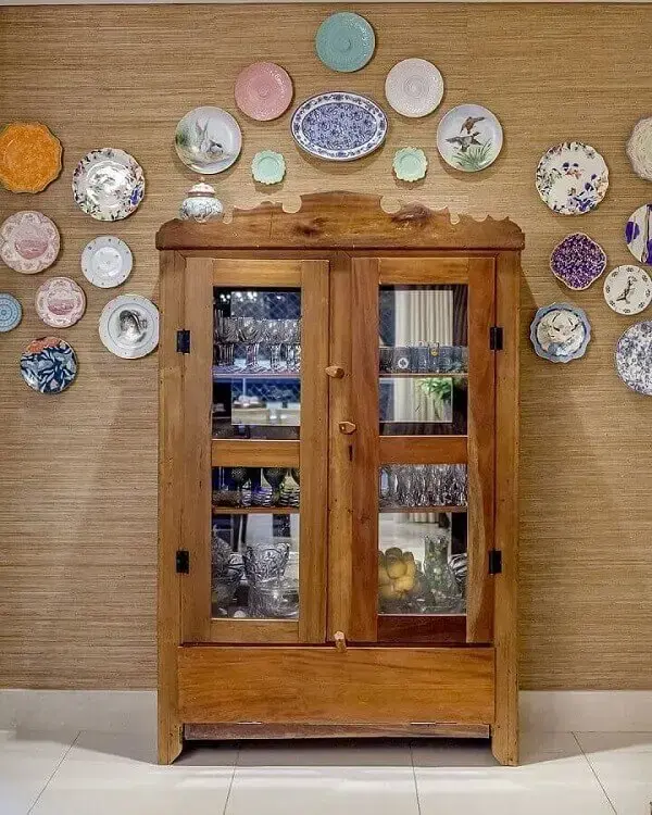 Os pratos de porcelana decoram a parede acima da cristaleira rústica