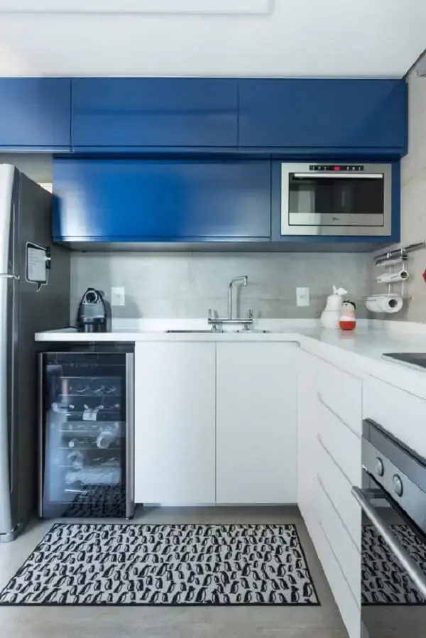 Parede de cimento queimado e armário aéreo basculante azul decoram a cozinha