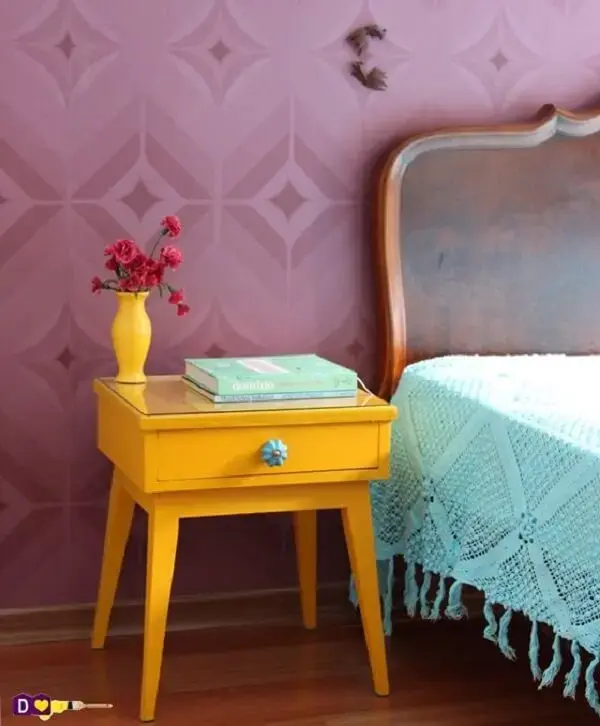 Quarto colorido com mesa de cabeceira retrô amarela, papel de parede roxo e colcha azul