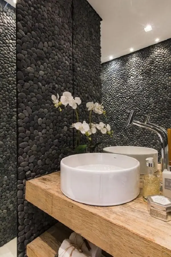 Revestimento de pedra feito com seixos pretos valoriza a decoração desse banheiro