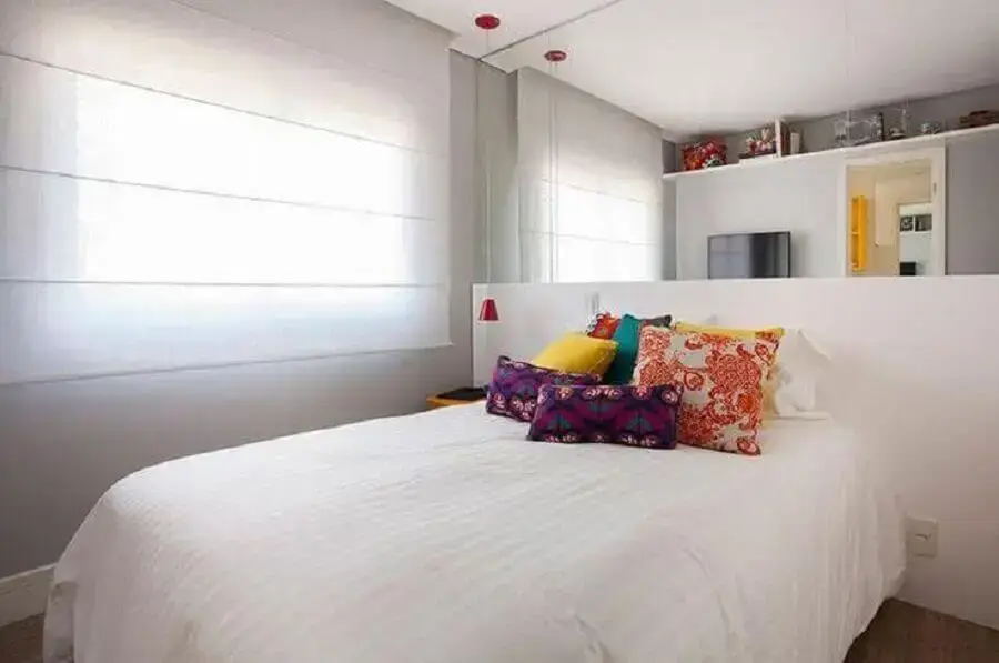 Almofadas coloridas para decoração de quarto de casal simples com parede espelhada