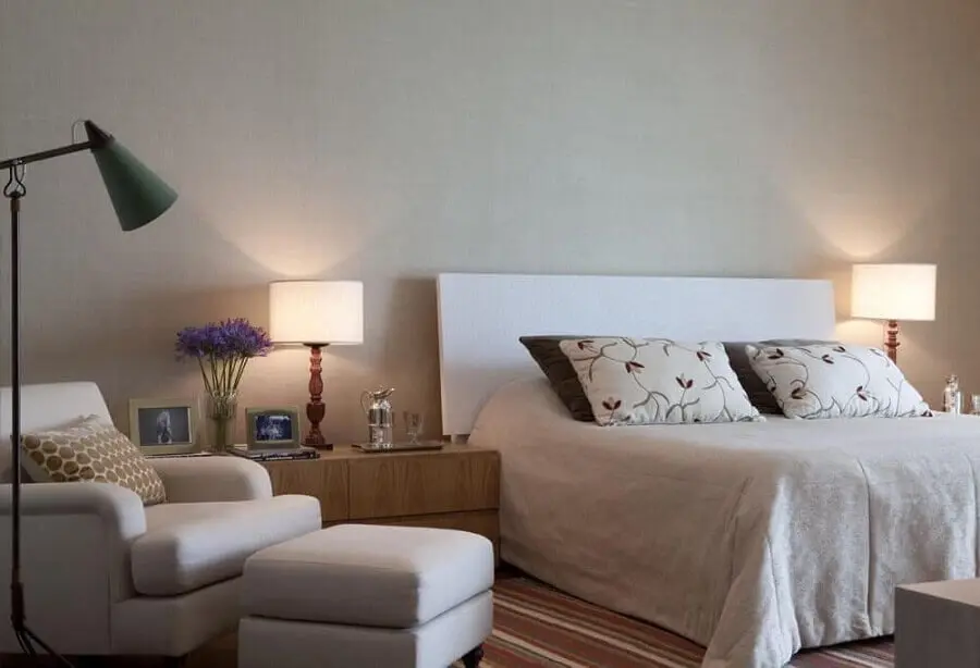 Cabeceira branca de madeira para quarto amplo decorado com poltrona confortável