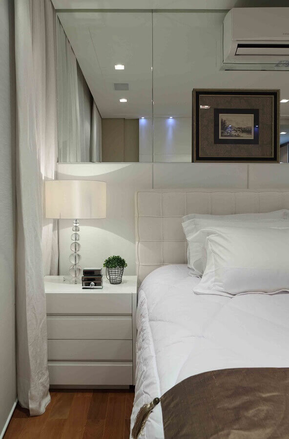Cabeceira estofada branca para quarto de casal decorado com parede espelhada