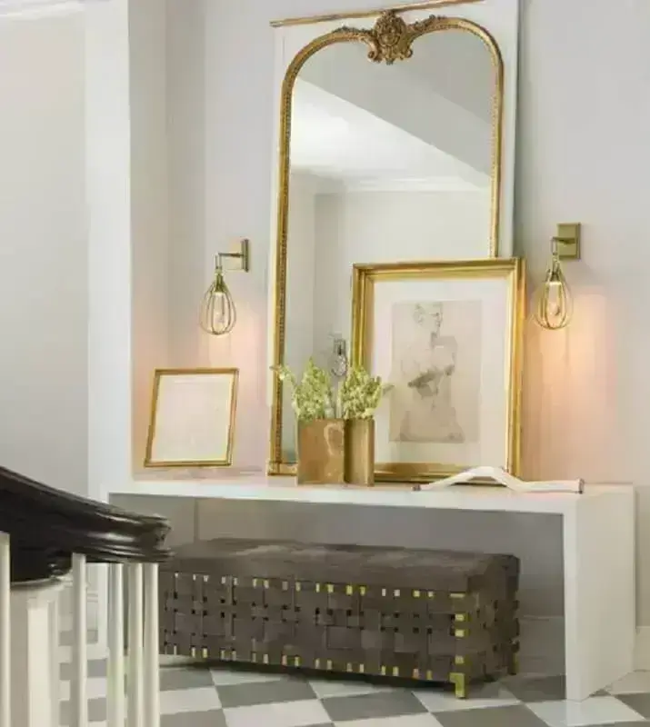 Decoração com espelho grande dourado sobre aparador simples branco